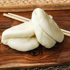 A steamed Chinese bao bun with its filling visible.