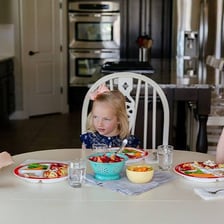 Children using good manners while eating at a table.