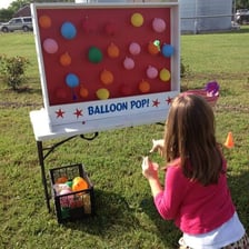 A carnival balloon-pop game with balloons arranged as targets