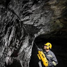A miner drilling into rock underground.