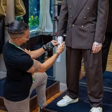 A tailor adjusts a suit jacket on a customer.