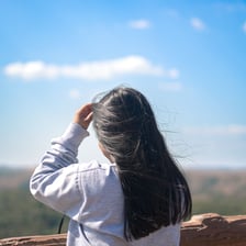 A person smiling while enjoying an outdoor view.