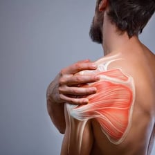 A person rubs their shoulders and back as if they are sore.