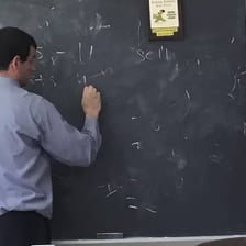 A teacher erasing writing from a chalkboard