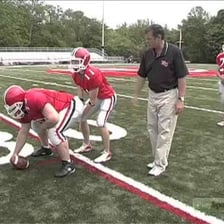A football center preparing to snap the ball to the quarterback.