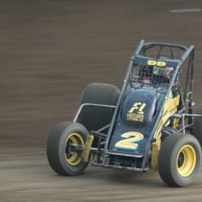 A sprint car races around a dirt track.