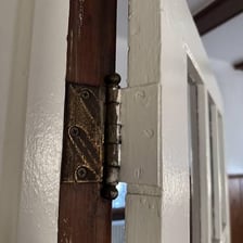 A door being detached from its frame by removing the hinges.