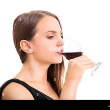 A person taking a small drink from a glass