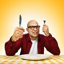 A person keeping a large portion of food to themself at a dinner table.