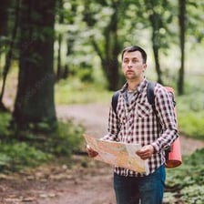 A hiker looking at a map while apparently lost in a forest
