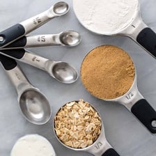 A measuring teaspoon beside ingredients and a recipe
