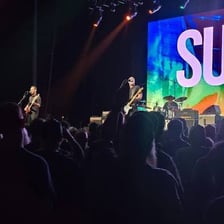 A rock band performing onstage in a concert setting.