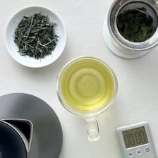 Loose tea leaves beside cups of brewed tea.