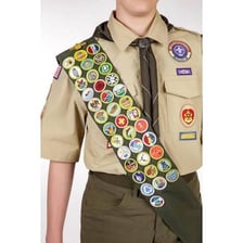 A fabric scout sash covered with pinned badges