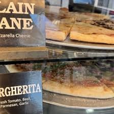 A casual pizzeria counter displaying individual pizza slices