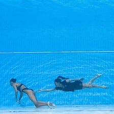 A person gesturing for someone to enter a swimming pool