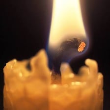 A candle wick burning beneath a small flame.