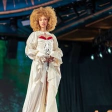 A stylish performer showing energetic confidence on stage.