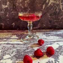 A Kir royale cocktail in a glass with a deep red color.