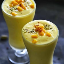 A glass of creamy Indian lassi is served with a straw.