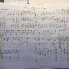 A handwritten musical score lies open on a desk.