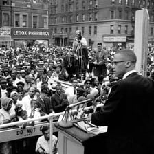 A speaker makes an expressive, passionate address to a crowd.