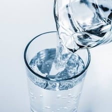 A drink being poured into a glass until it is full