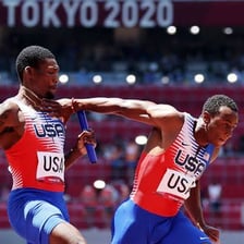 A relay runner passing a baton to a teammate.