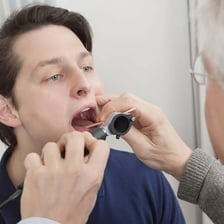 An ear, nose and throat specialist examining a patient's throat