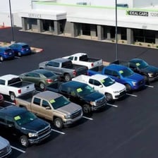 Cars parked in rows at an automobile dealership.