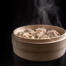 Shumai dumplings cooking in a bamboo steamer