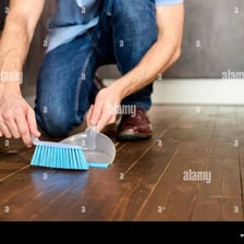 A person using a broom to sweep dust from a floor.