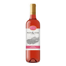 Clusters of Zinfandel grapes beside a glass of pink white Zinfandel wine.