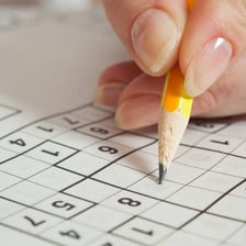 A person working through a sudoku puzzle with a pencil.