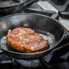 Food being roasted in a pan on a stovetop.