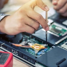 A computer technician helping someone troubleshoot a laptop