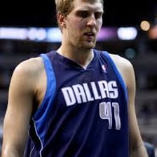 Dallas Mavericks players in team uniforms on a basketball court.