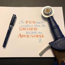 A writing pen and a sword shown side by side.