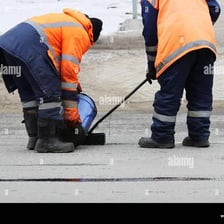 A road crew applying dark asphalt to pave a roadway