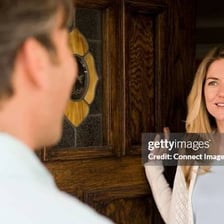 A person walking toward a front door after a doorbell rings
