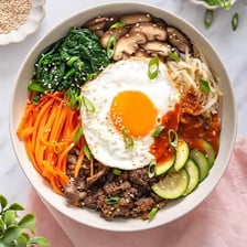 A bowl of bibimbap with rice beneath its toppings.