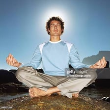 A person meditates while sitting with legs crossed.