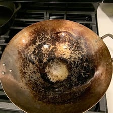 A well-used wok with a dark seasoned patina on its cooking surface.