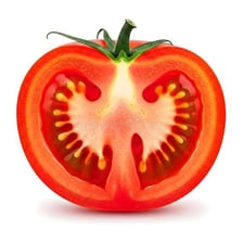 A ripe tomato is cut open to show its seed-filled interior.