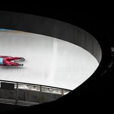 A luge athlete racing feetfirst down an icy track