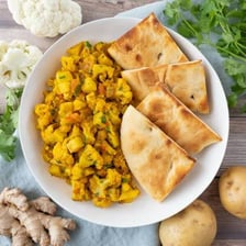 A serving of aloo gobi accompanied by naan bread.
