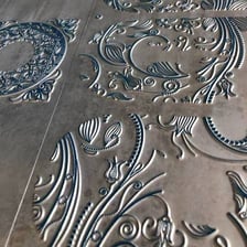 An artist engraving a design into a metal plate.