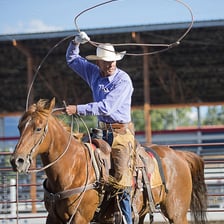 A rodeo rider swinging a lasso.