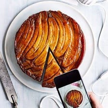 An upside-down banana cake being inverted to reveal bananas on top