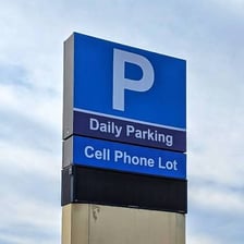 A cellphone lot sign near an airport where drivers wait for arriving passengers.